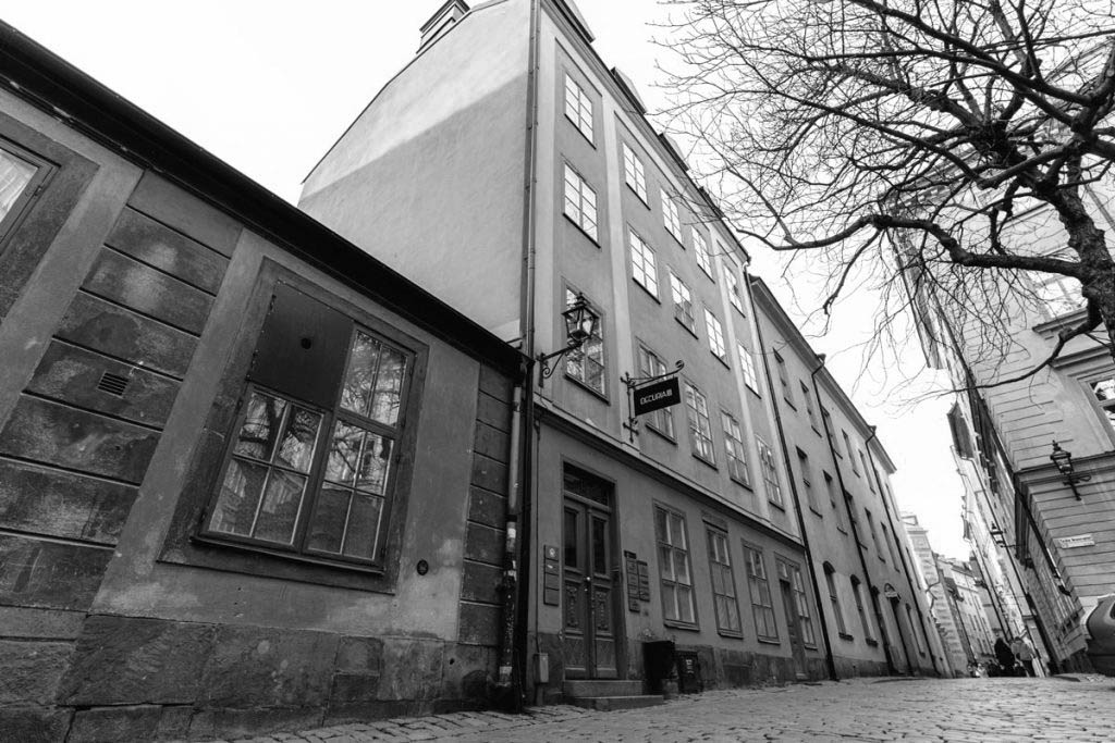 Svartvitt fotografi på en
              byggnad i tegelsten: här är vi!